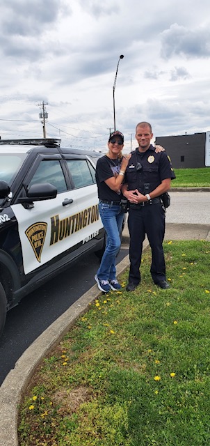  Two people posing next to a police car at a community event