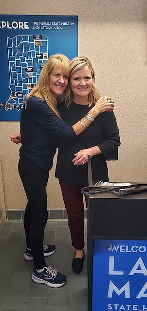  Two women smiling together at a social assistance event