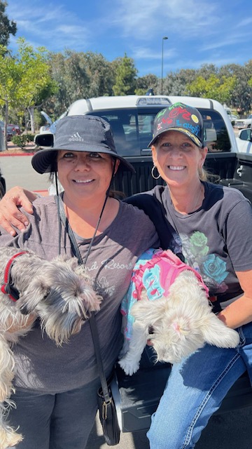  Two women with dogs posing for a picture at a social assistance event