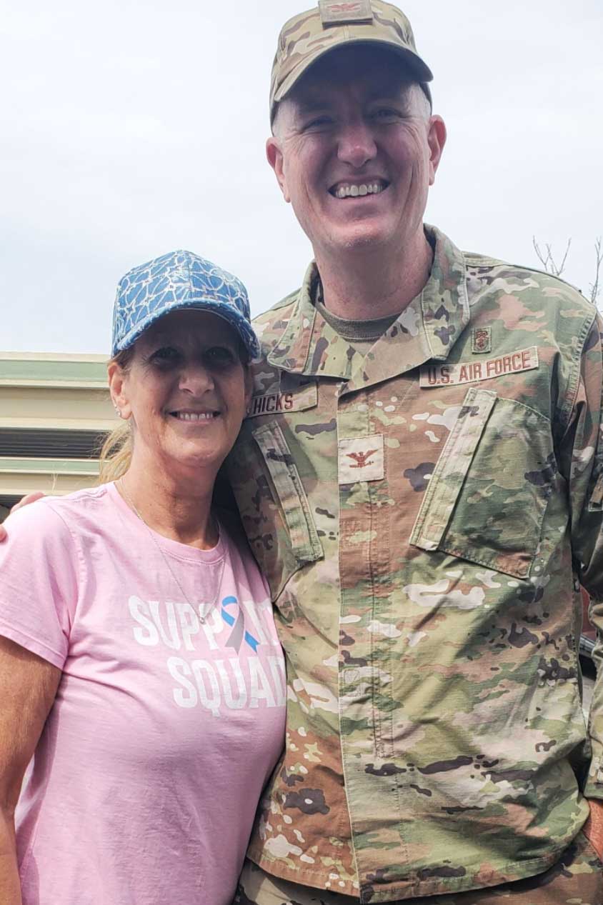 A person in a military uniform alongside someone in a pink shirt at a community event