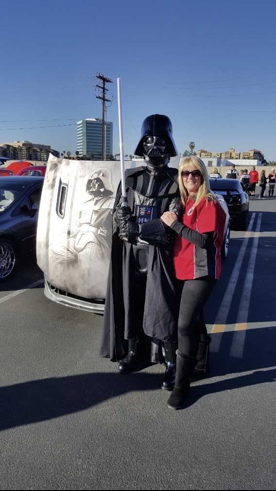 An individual standing beside a character statue at a Just Believe Foundation event