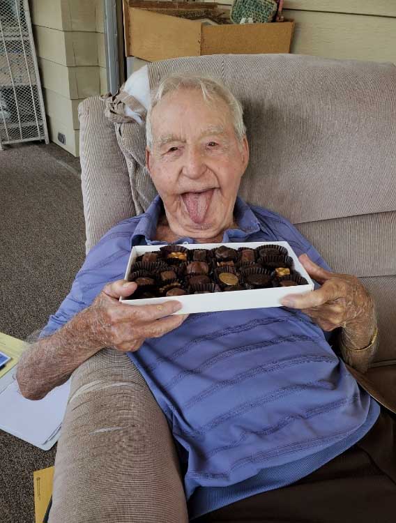 An elderly person holding a box of chocolates at a community service event