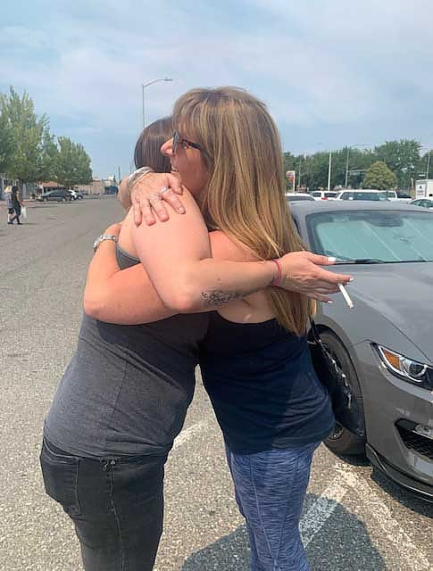 Two women hugging each other during a community support event