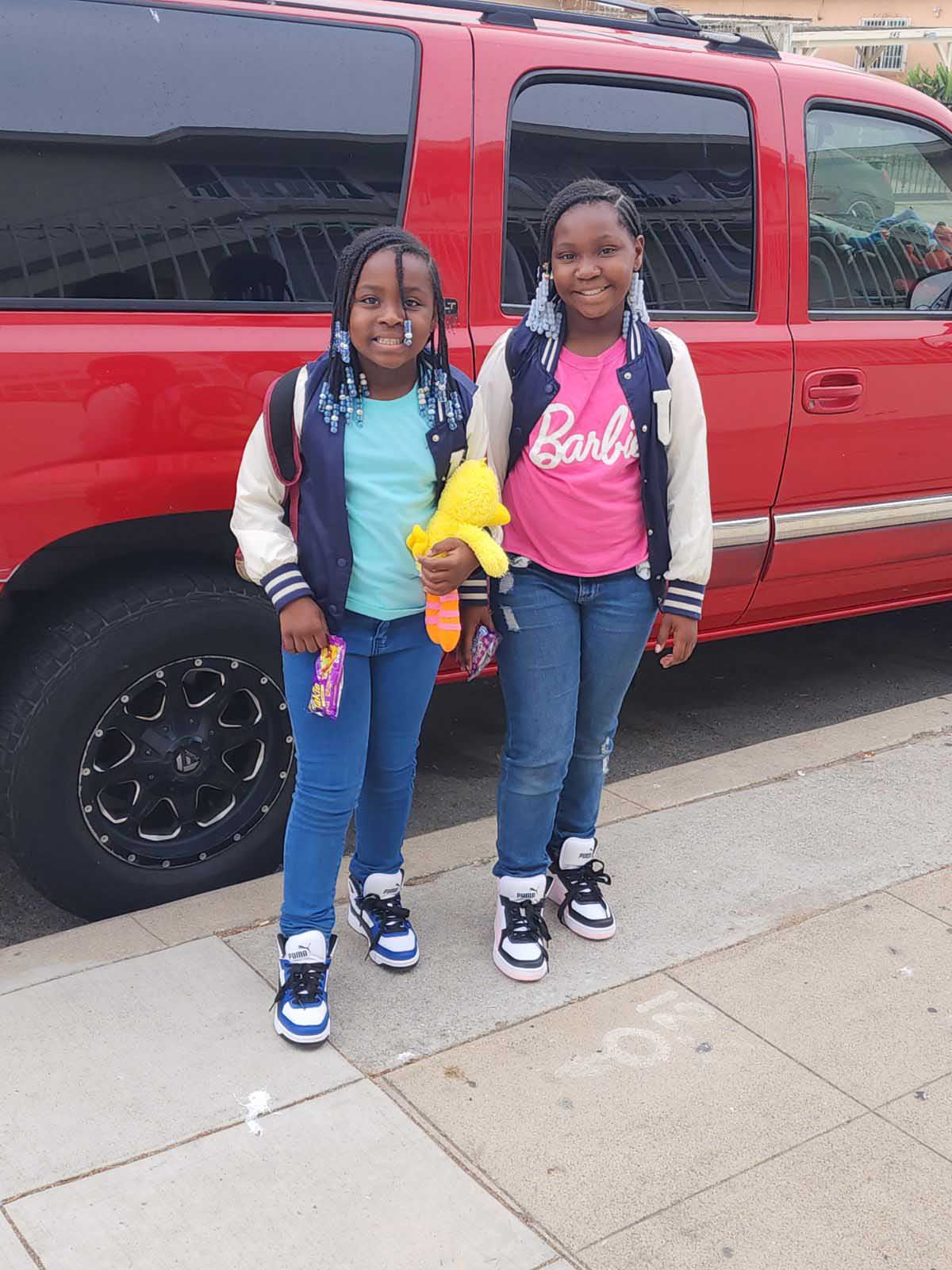 Two girls standing next to a red truck during a nonprofit event